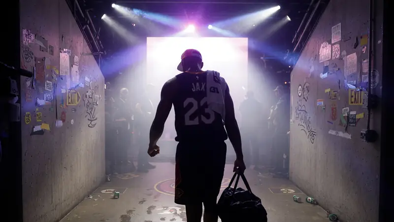 Player walking through a smoky arena tunnel toward stage light