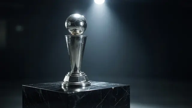 Tournament trophy on a black marble pedestal under a single overhead spotlight